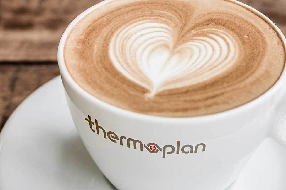 Latte art heart in white cup on wooden table